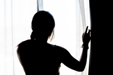 a woman in silhouette looking out of the window