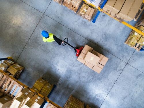 warehouse worker pulling forklift with products